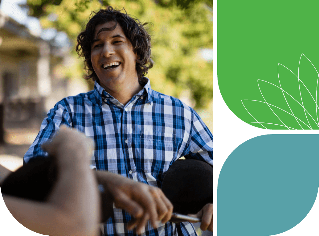 A man with curly hair is smiling at another person just off to the left